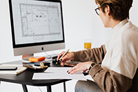 An expert custom home builder in New Jersey reviews a floor plan on their computer monitor.