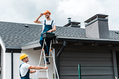 Employees of chimney service Belmar company Baron's Chimney Service at work on a grey roof